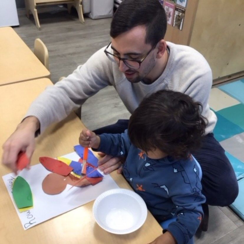 Man and child doing arts and crafts at a table, both focused on the project.