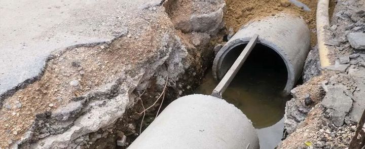 Tubi in una trincea attraversati da acqua, cemento e terra.