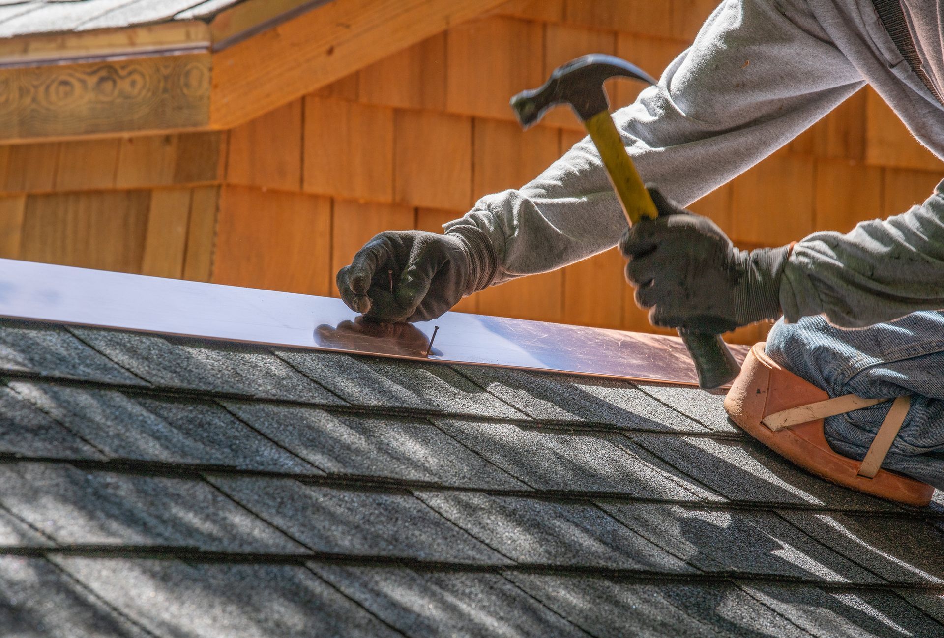 A man is working on a roof with a hammer.