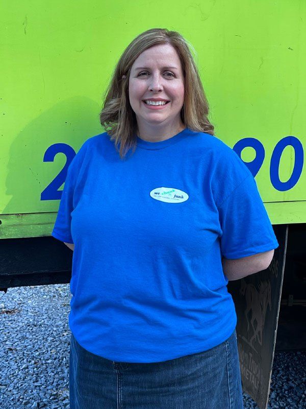 A woman in a blue shirt stands in front of a yellow truck with the number 2090 on it