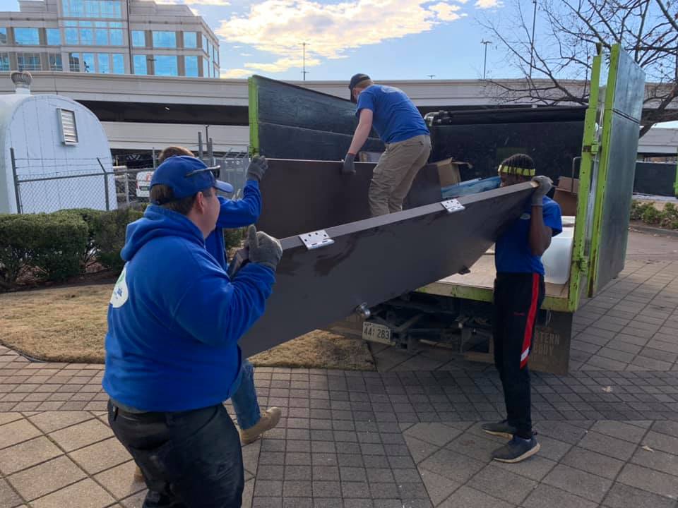 A group of people are carrying a large piece of furniture into a truck.
