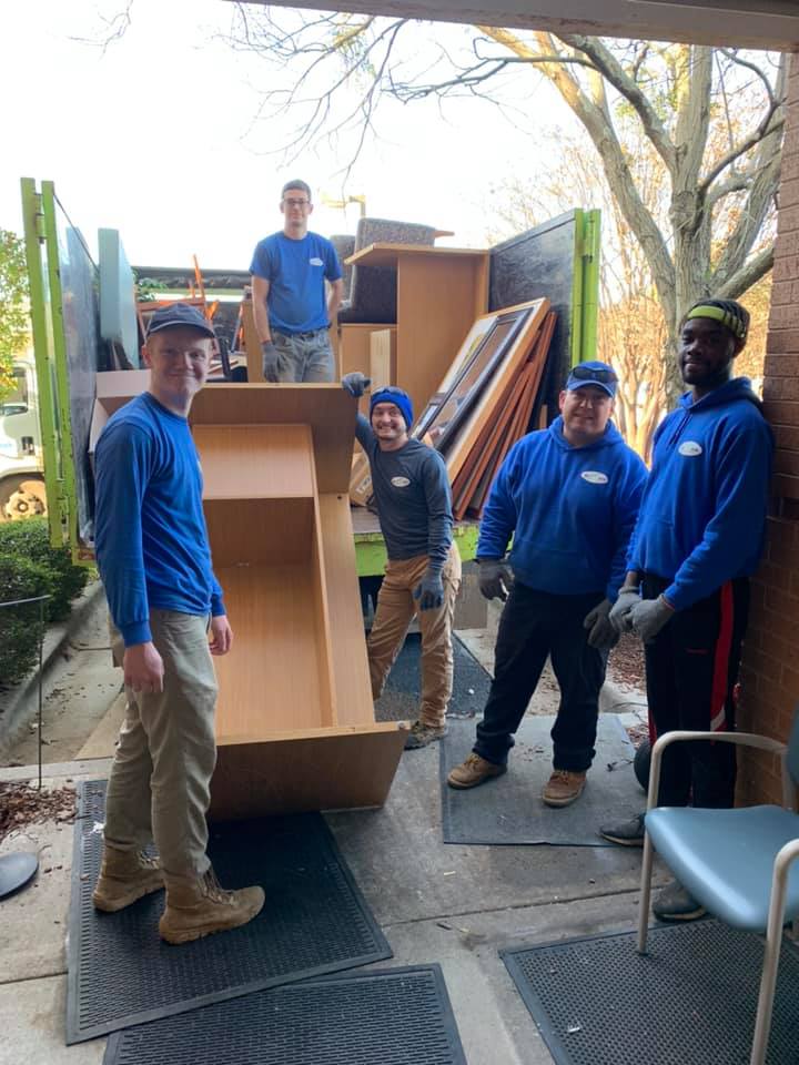 A group of men are standing in front of a moving truck.