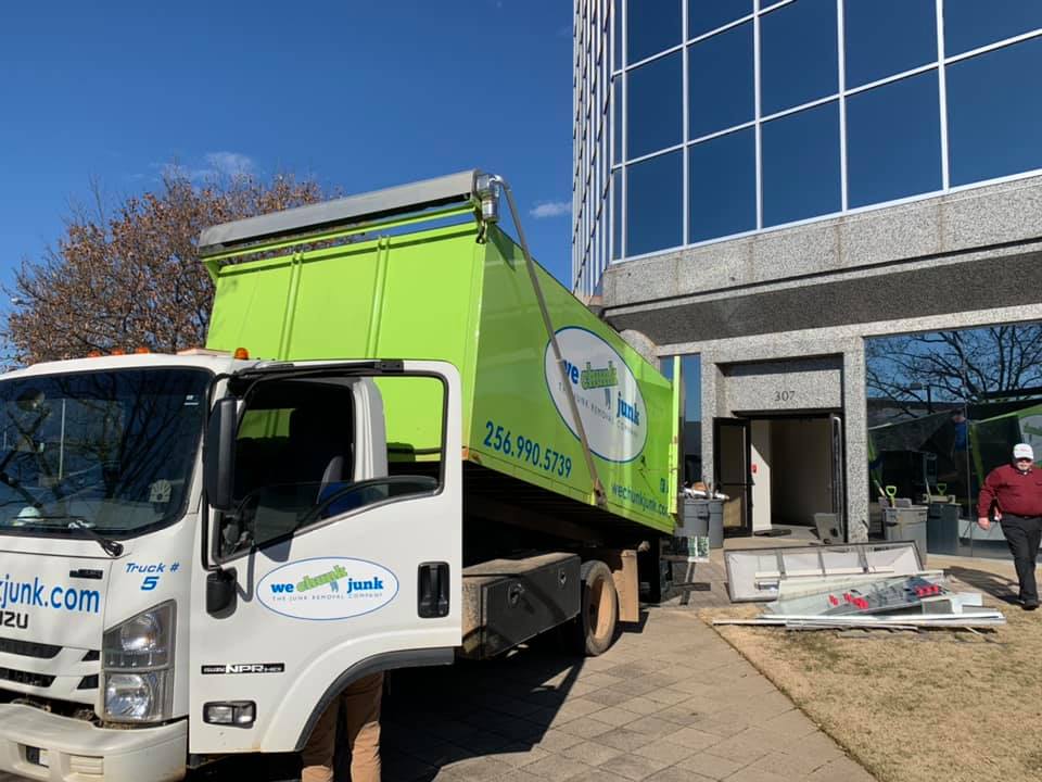 A green and white truck is parked in front of a building.