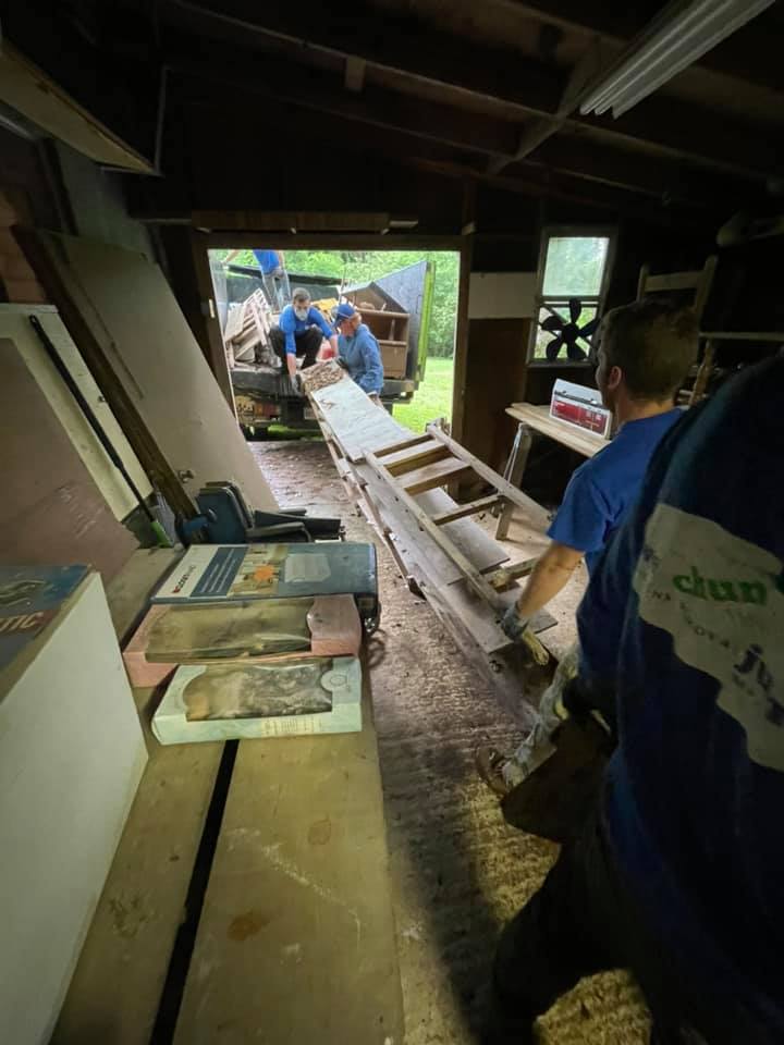 A group of men are working in a garage with a ladder.