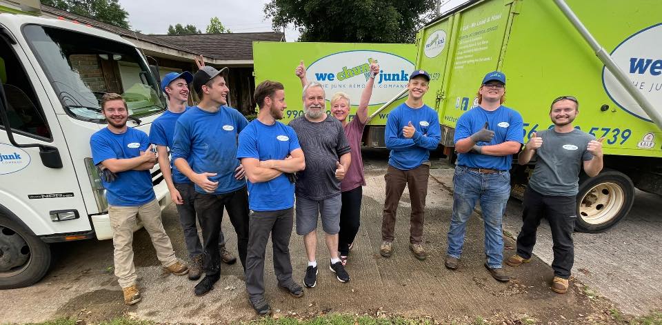 A group of men are posing for a picture in front of a junk truck.