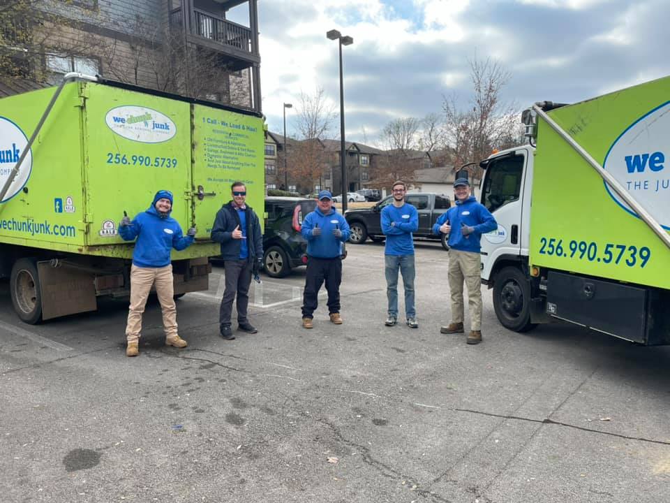 A group of men are standing in front of a green truck.