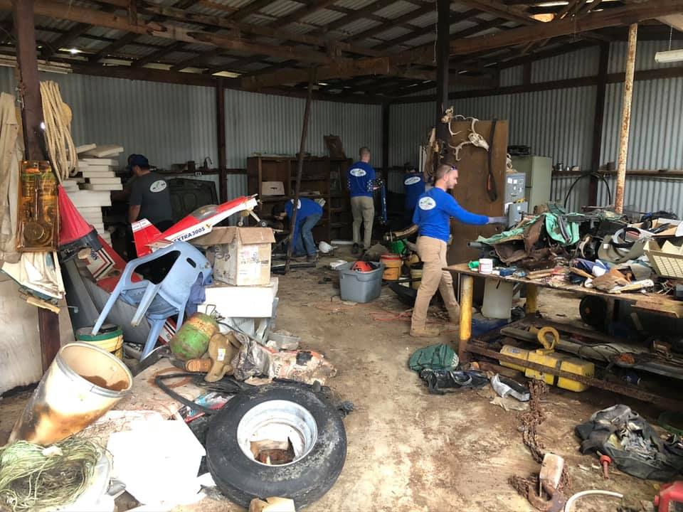 A group of people are working in a messy garage.