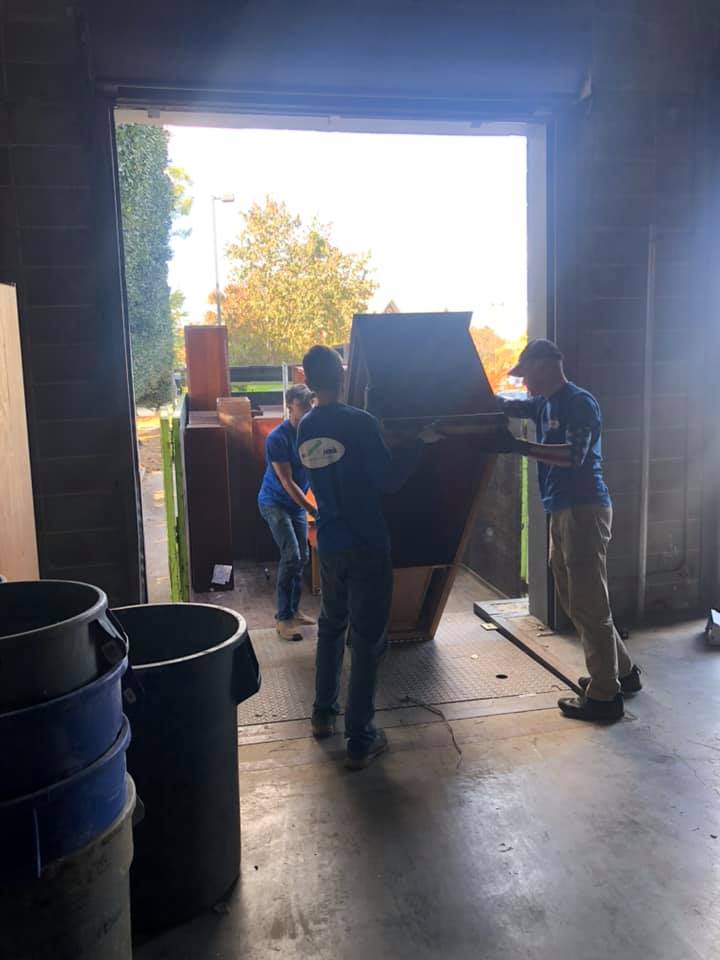 A group of people are moving a piano into a garage.