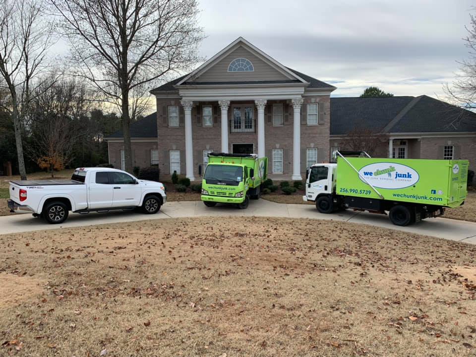 Three trucks are parked in front of a large house.