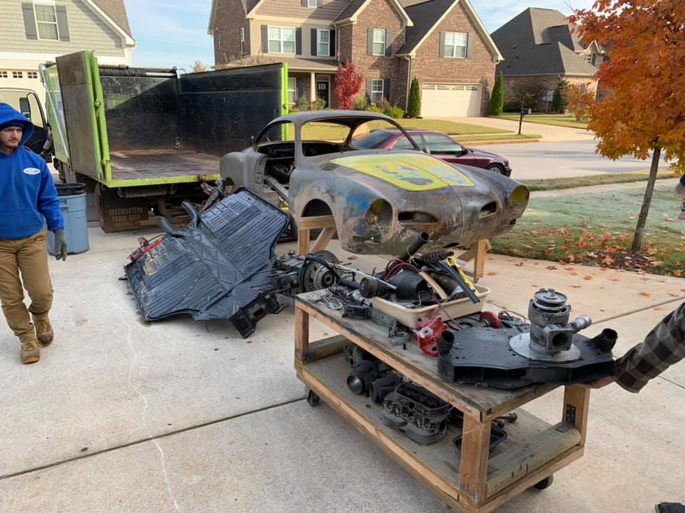 A man is pushing a cart with a car on it.