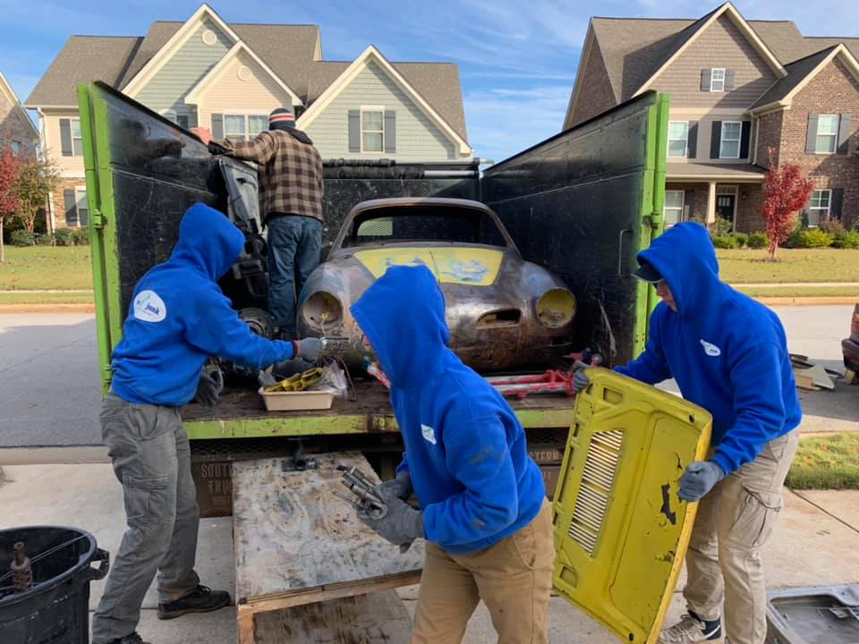 A group of people are loading a car into a truck.