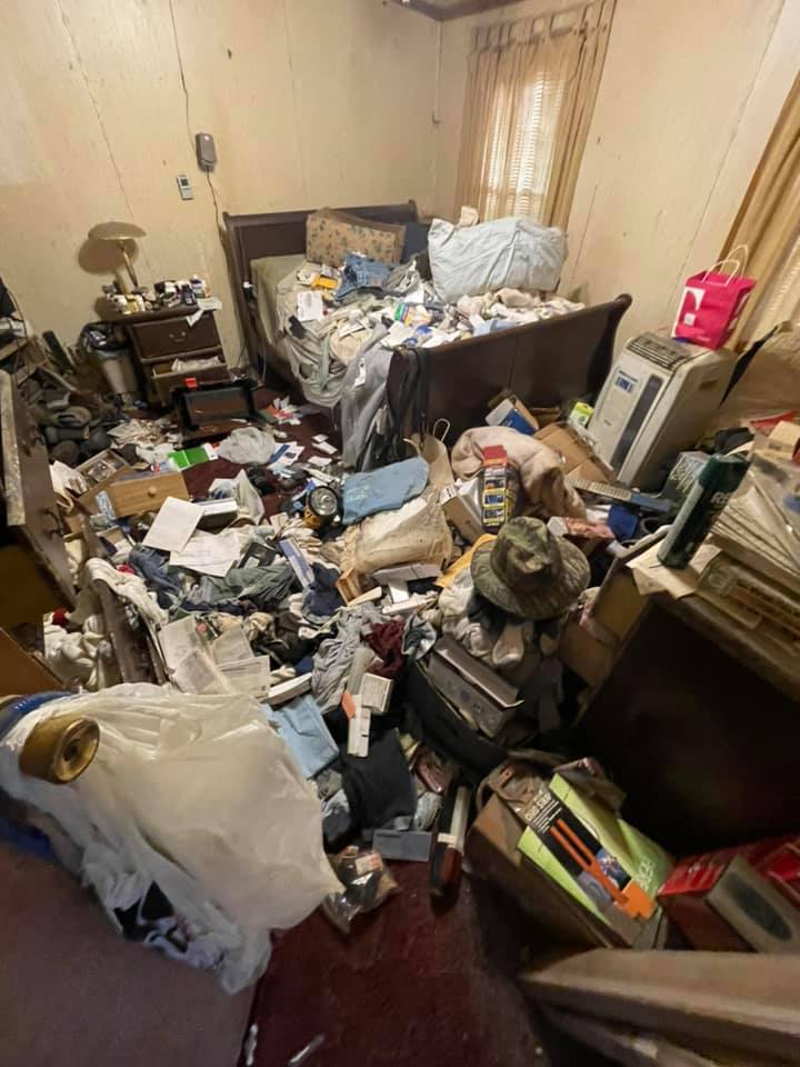 A bedroom filled with lots of junk and a bed.