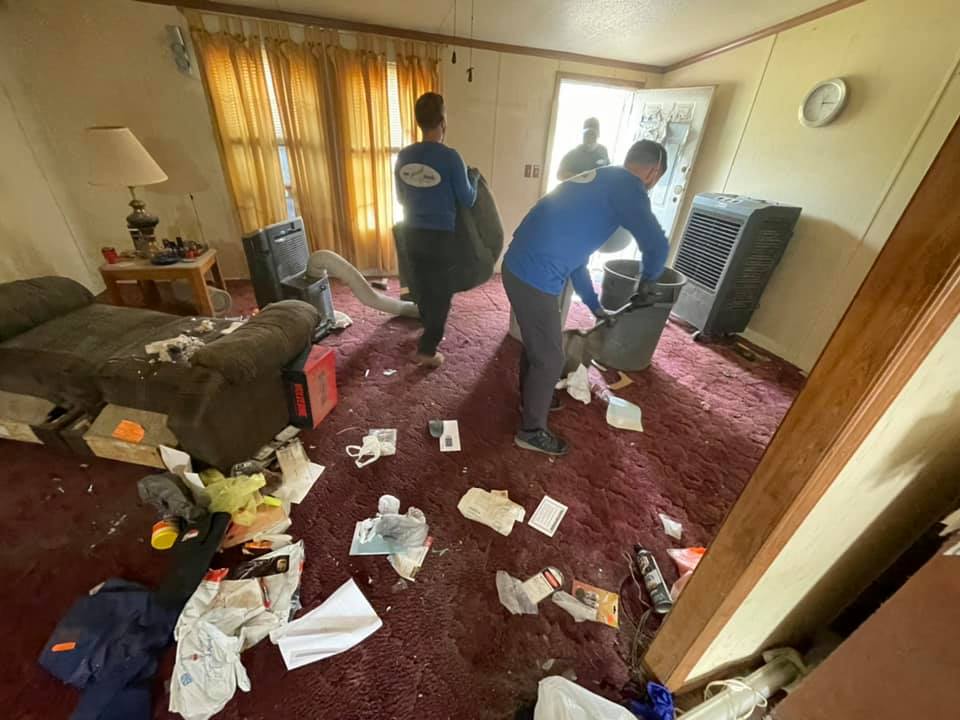 A group of people are cleaning a messy living room.
