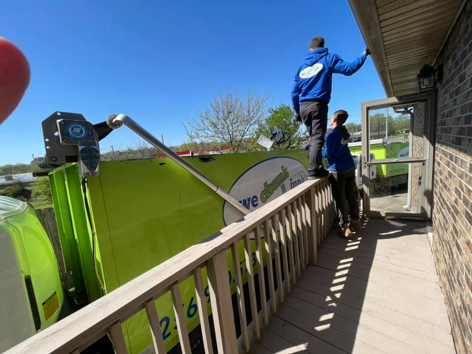 A green garbage truck with the number 26 on it
