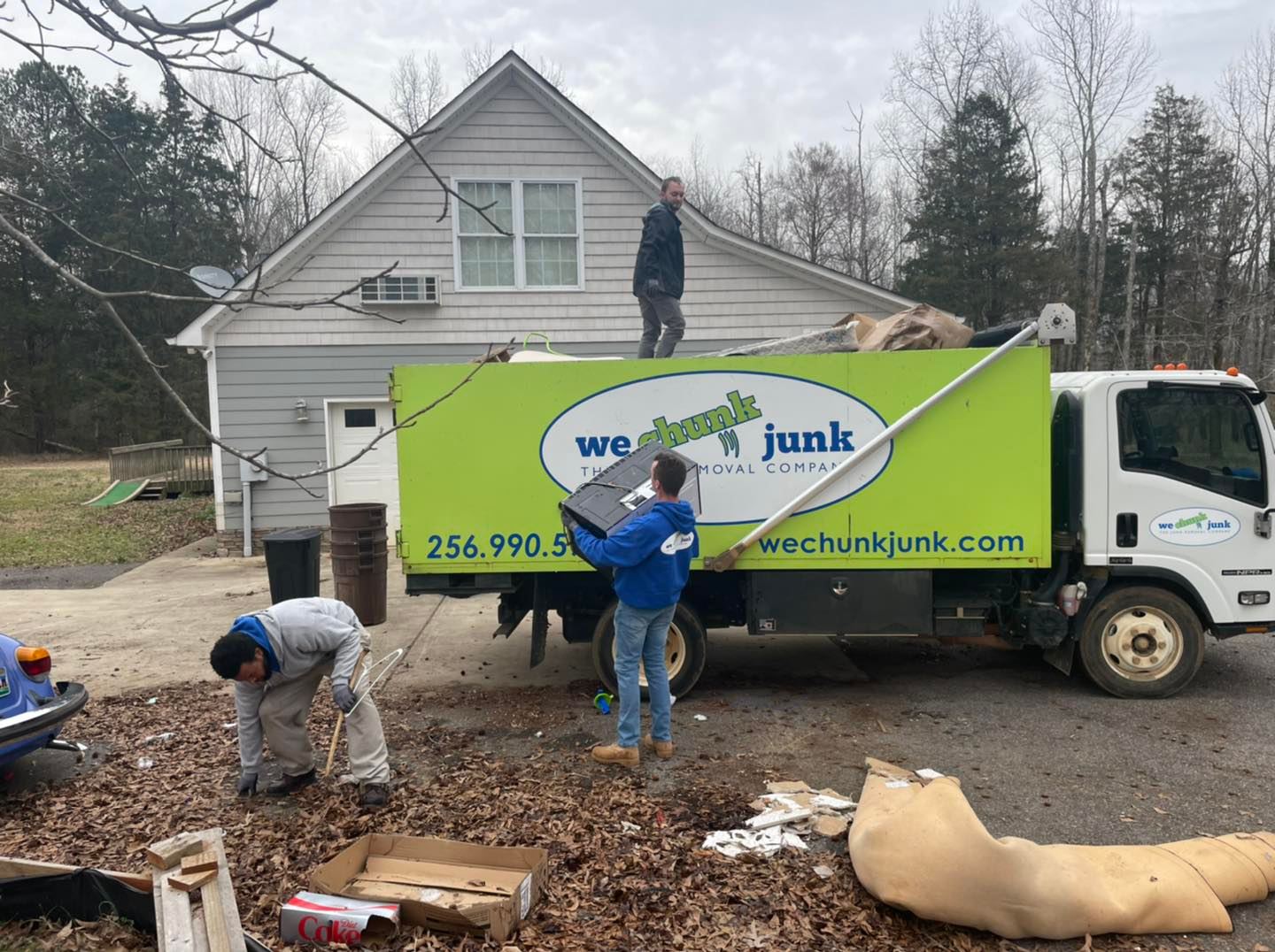 A junk truck is parked in front of a house.