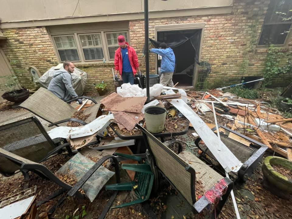 A group of people are standing in front of a pile of trash.