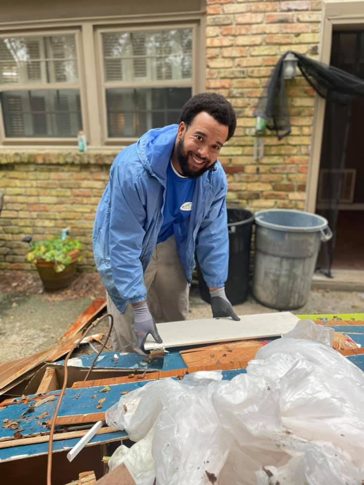 A man in a blue jacket is standing in front of a brick building.