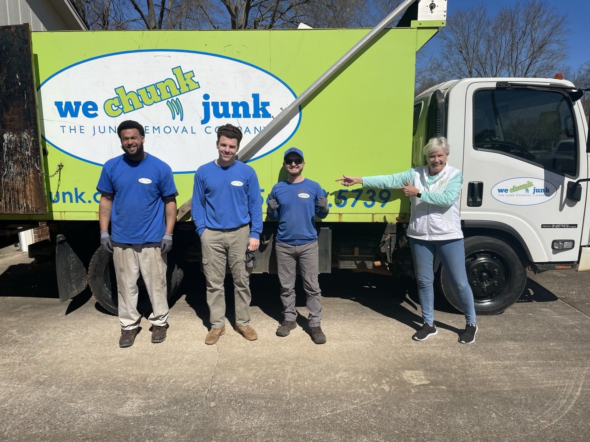 A group of people standing in front of a junk truck.