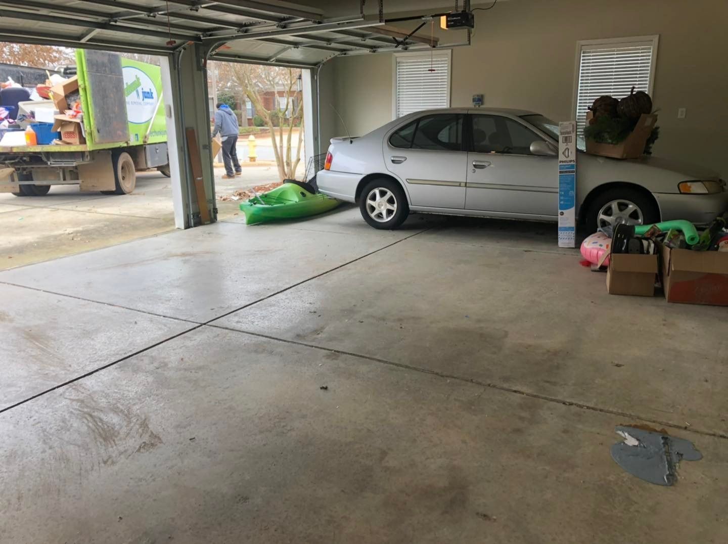 A car is parked in a garage next to a green truck.