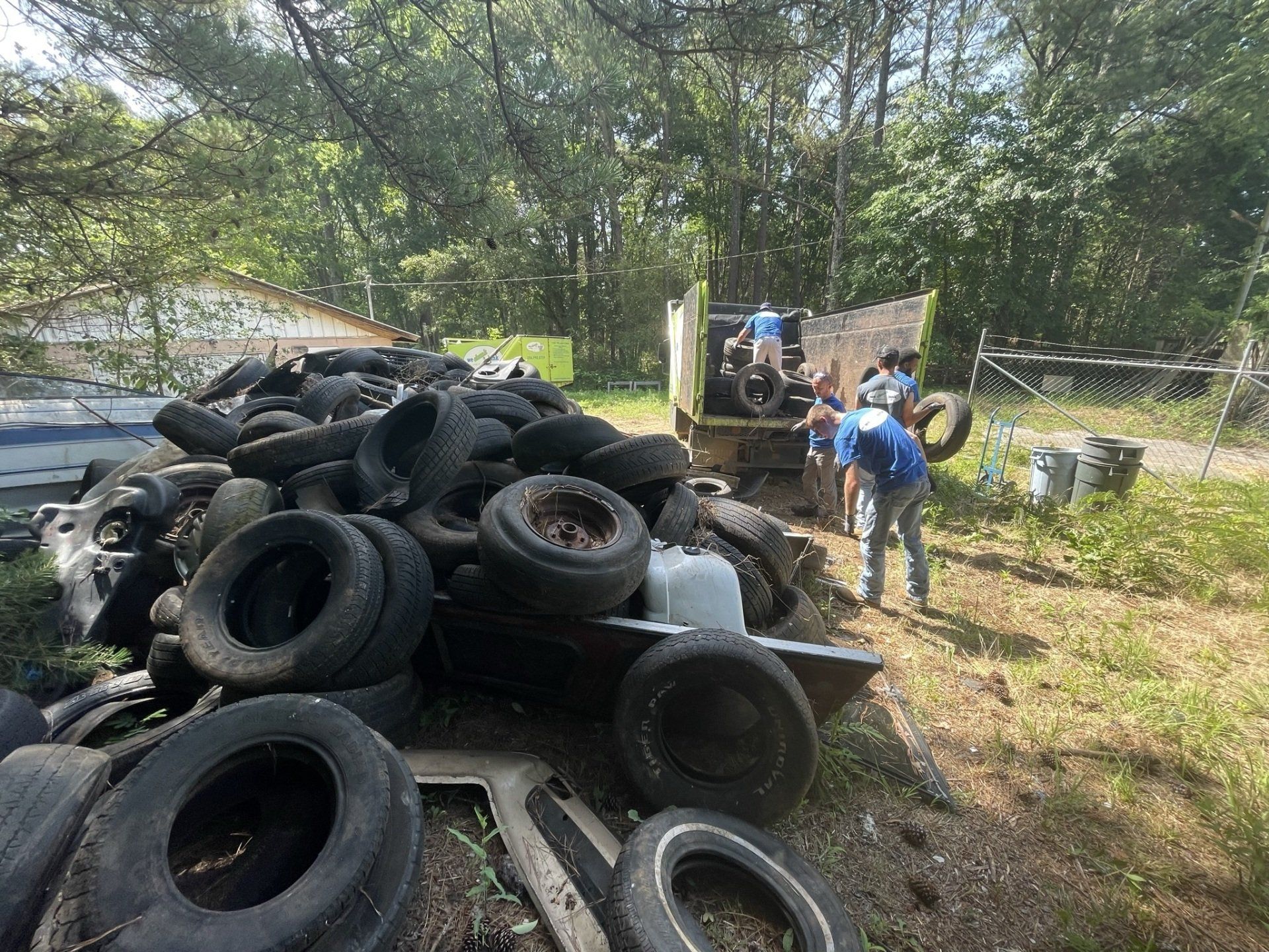A group of people are standing around a pile of tires.