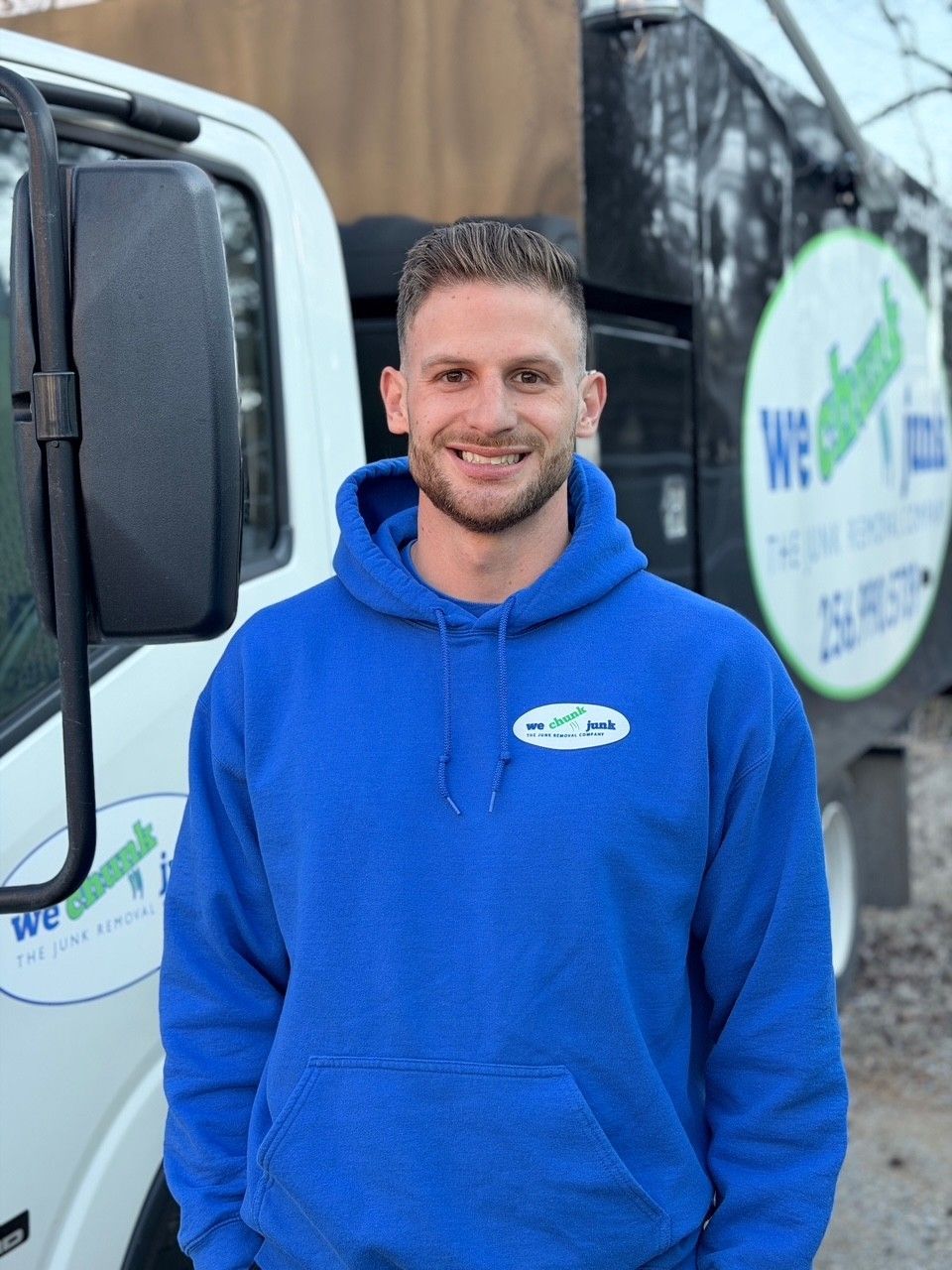 A woman in a blue shirt stands in front of a yellow truck with the number 2090 on it
