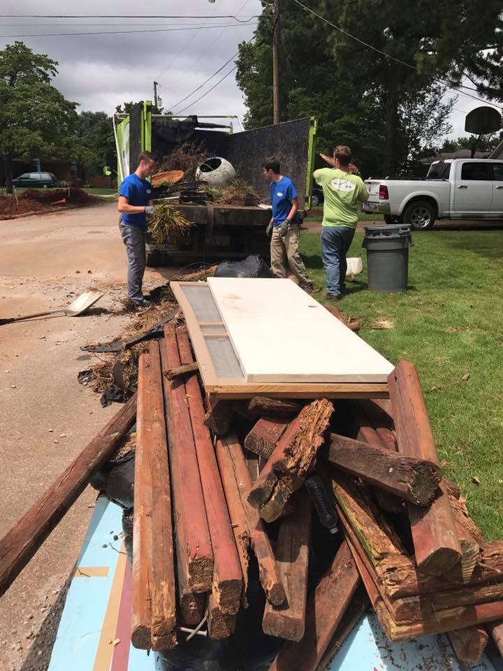 A group of people are standing around a pile of wood.