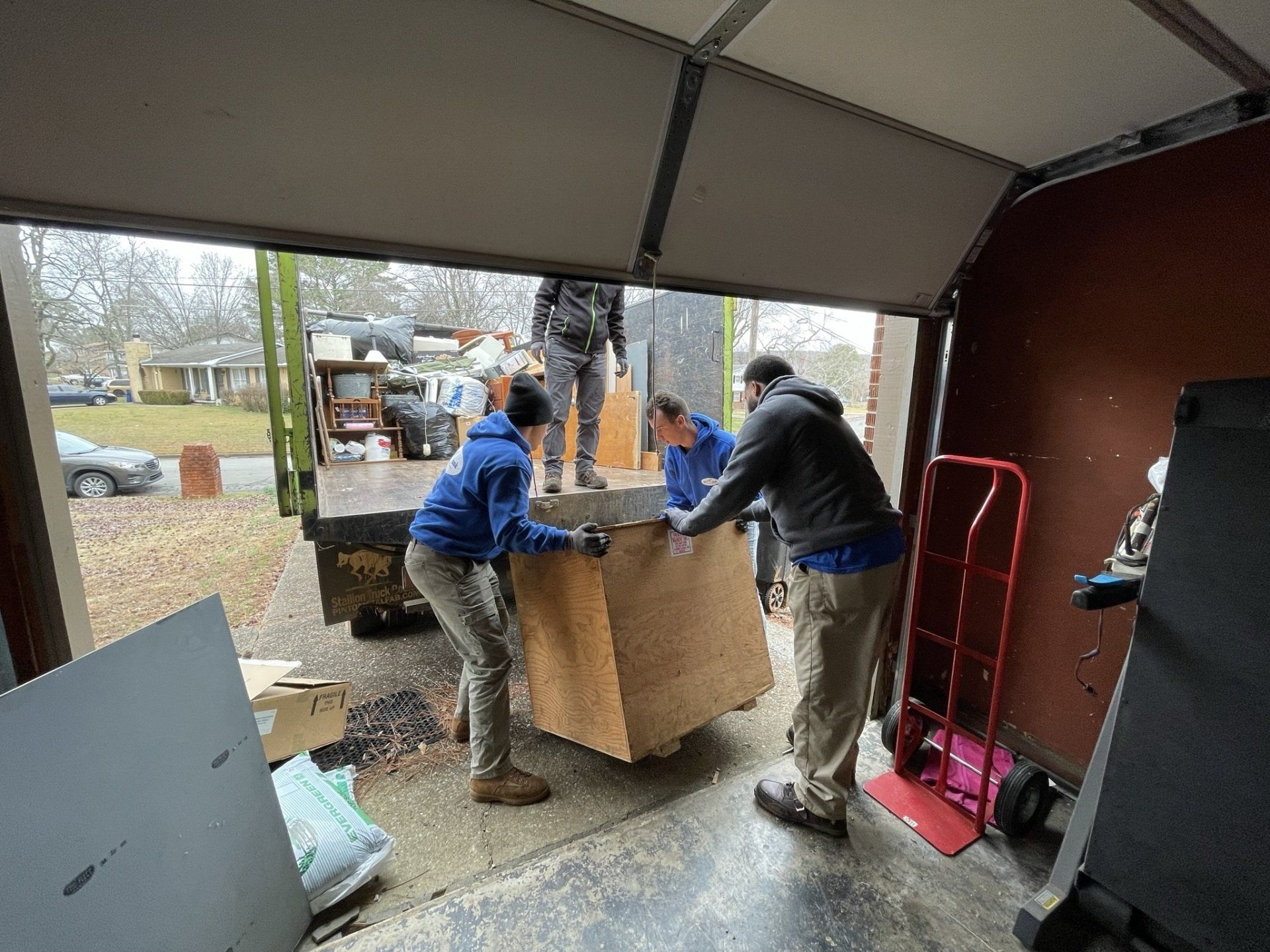 A group of people are loading a box into a truck in a garage.