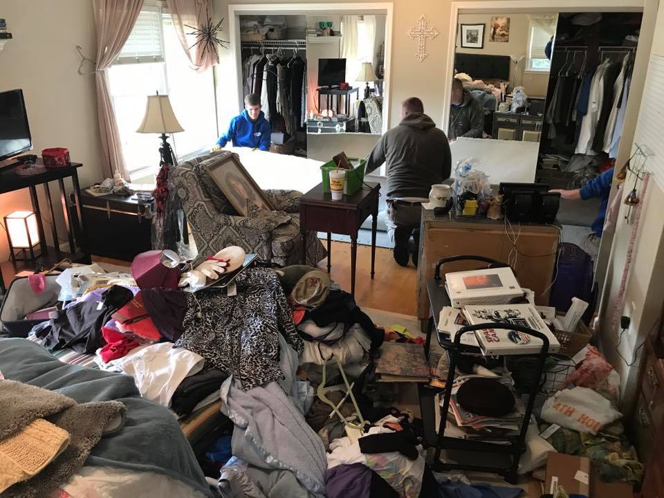 A living room filled with lots of clothes and furniture.