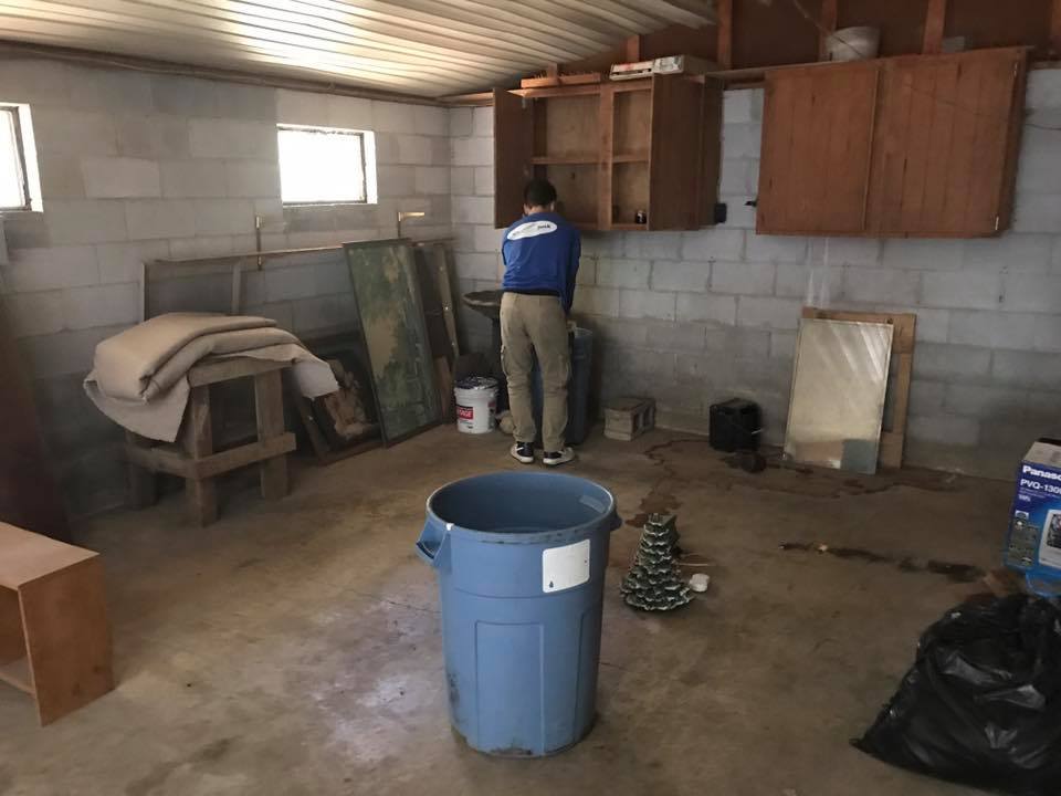 A person is standing in a room with a blue trash can.