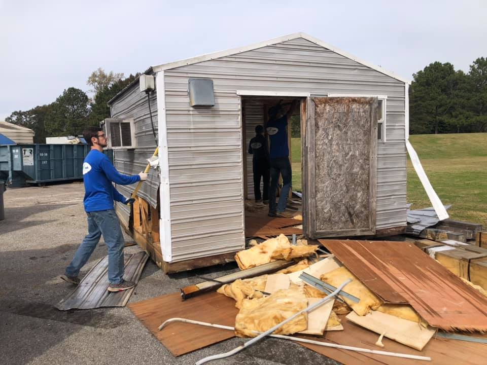 A man is standing in front of a shed that is being demolished.