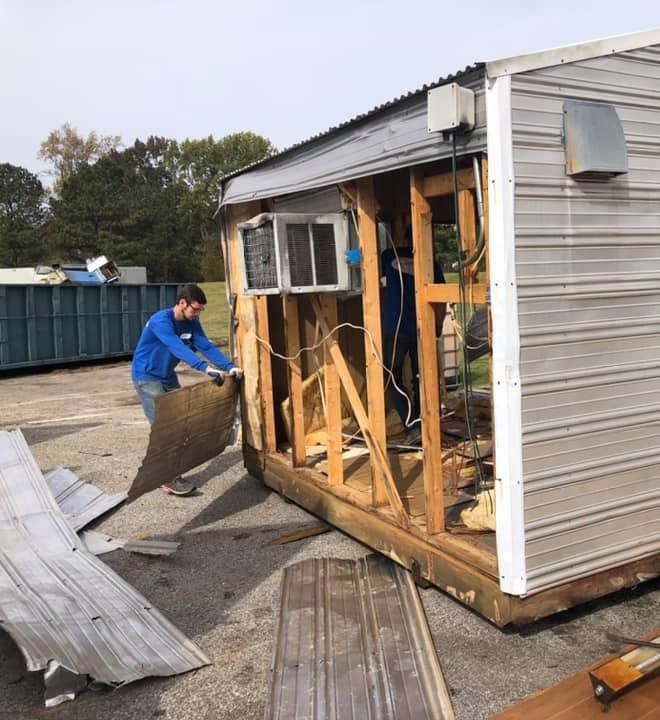 A man in a blue shirt is working on a shed