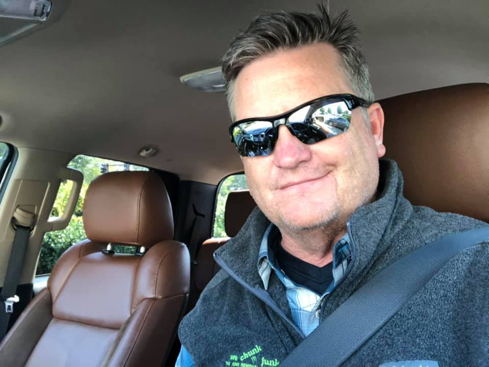 A man wearing sunglasses is sitting in the driver 's seat of a car.