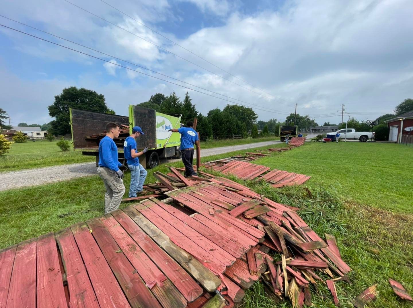 A group of men are standing next to a pile of red wood.