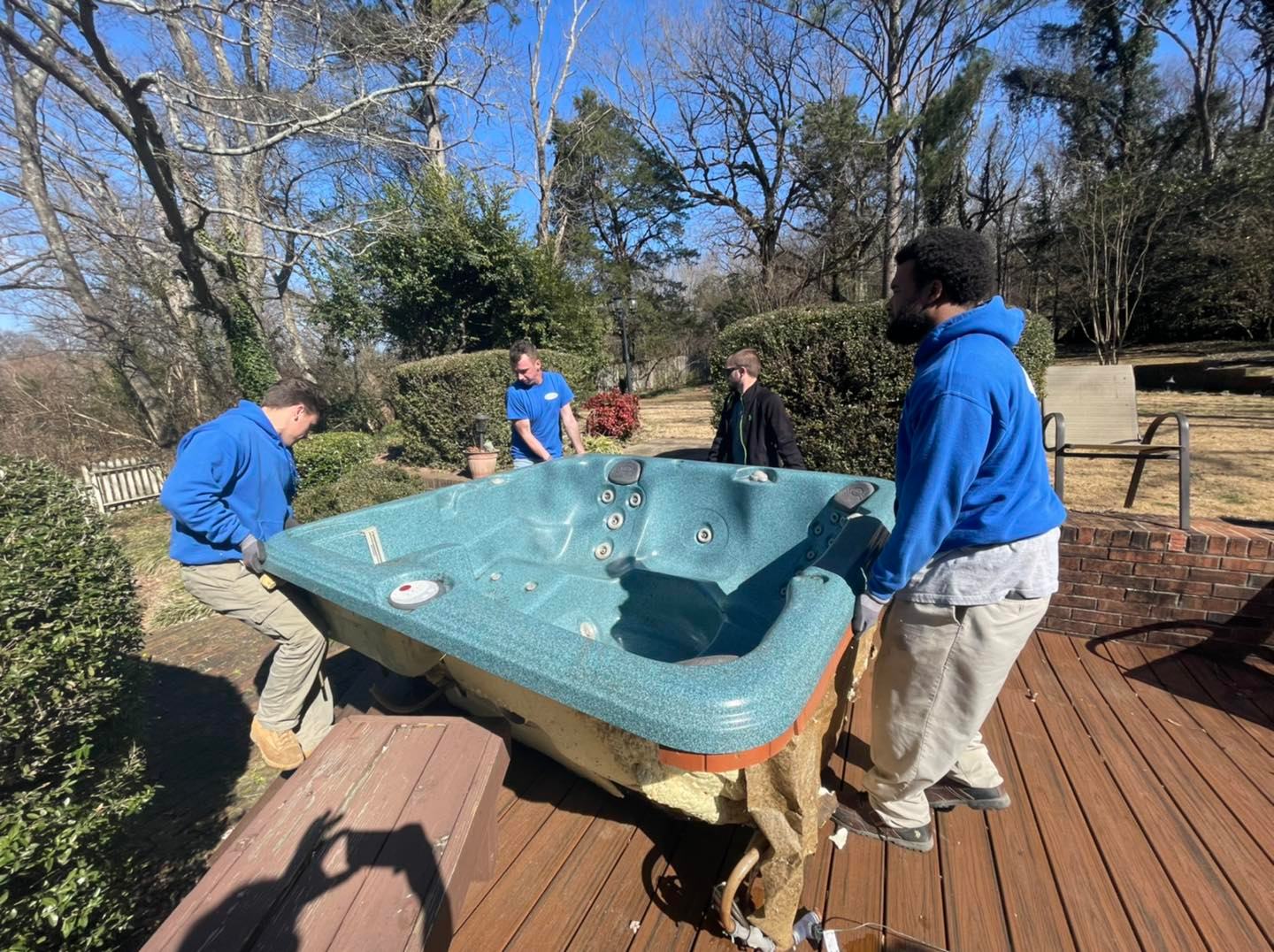 A group of men are carrying a hot tub on a wooden deck.