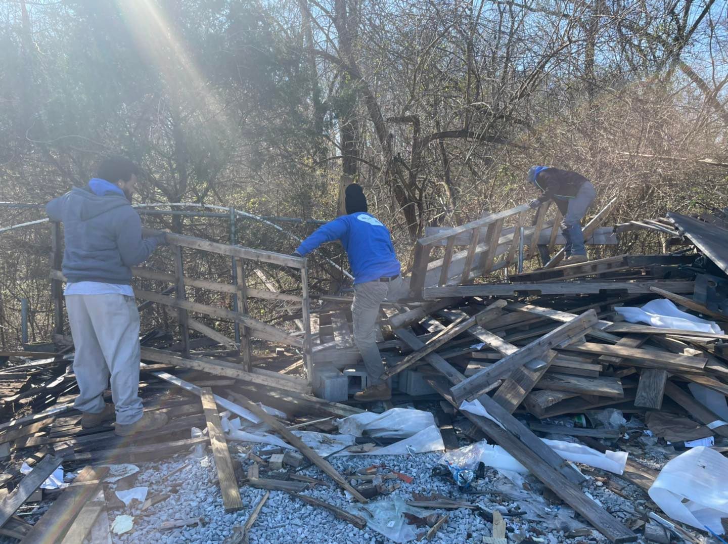 A group of people are working on a pile of wood.