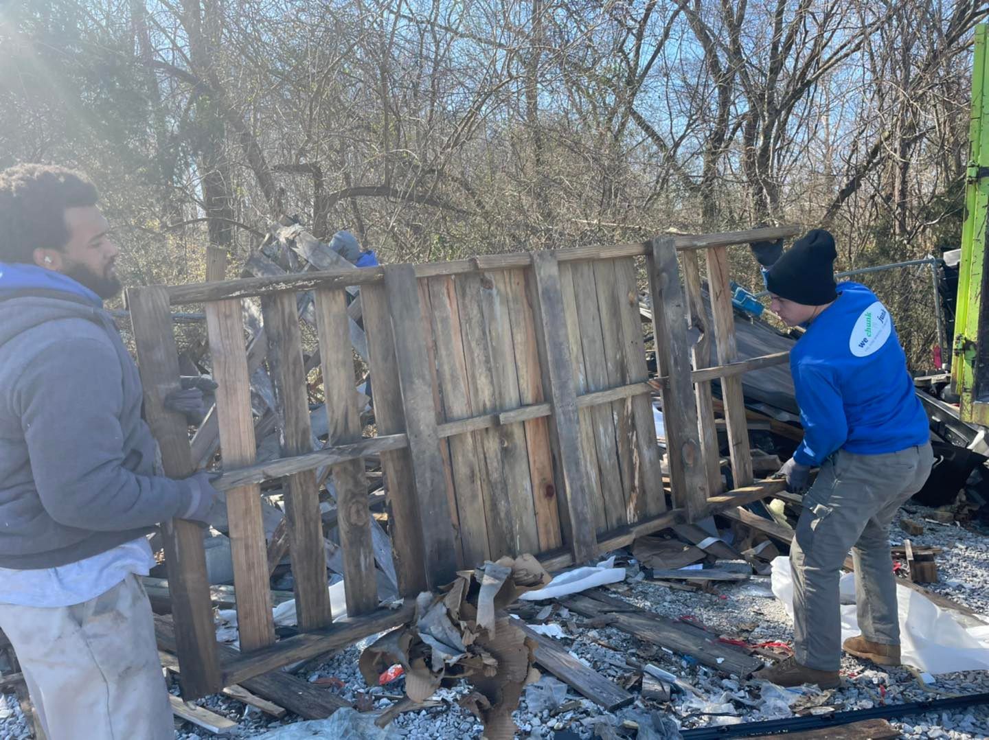 Two men are working on a wooden fence in the snow.