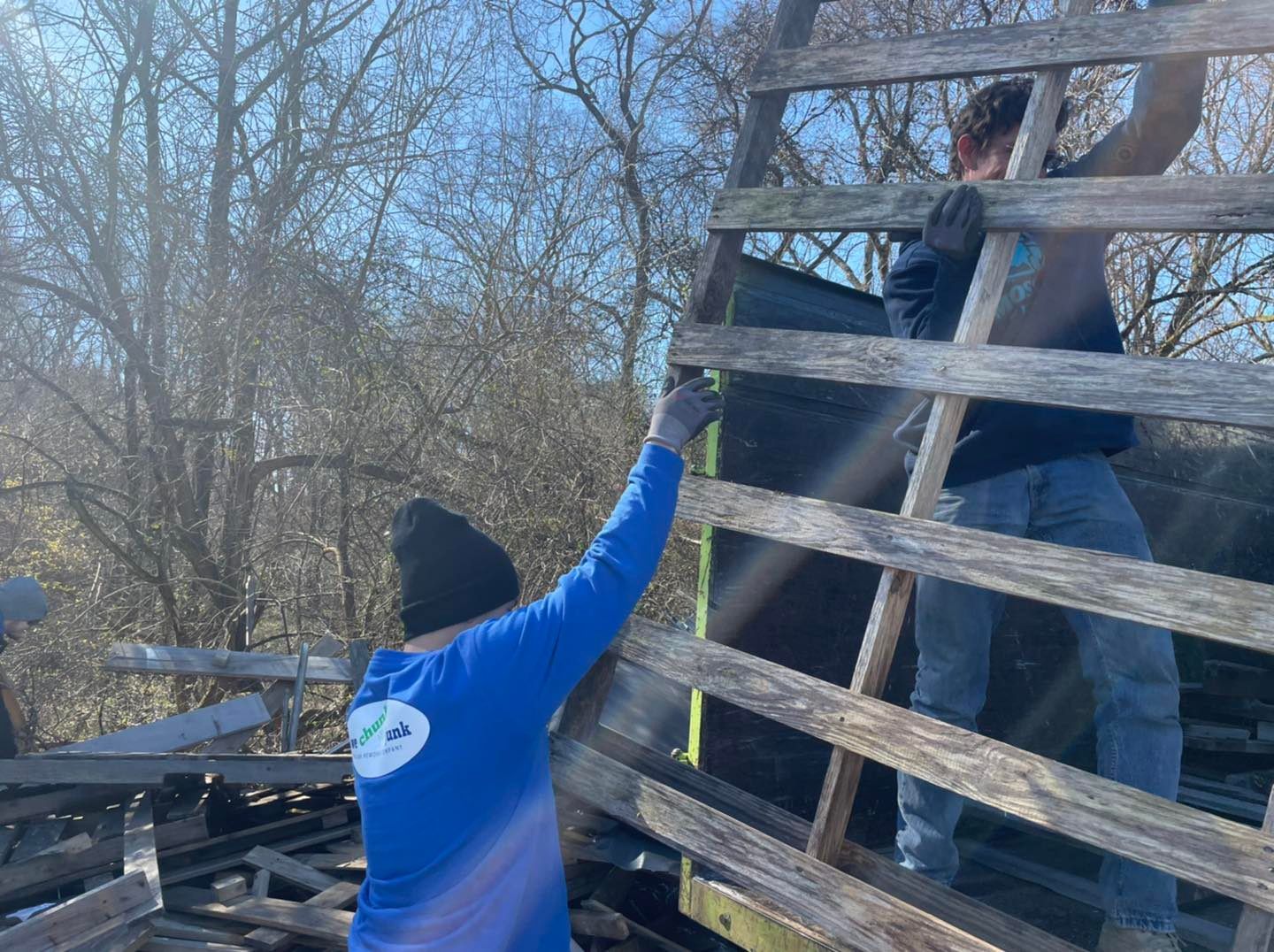 Two men are measuring a wooden fence with a tape measure.