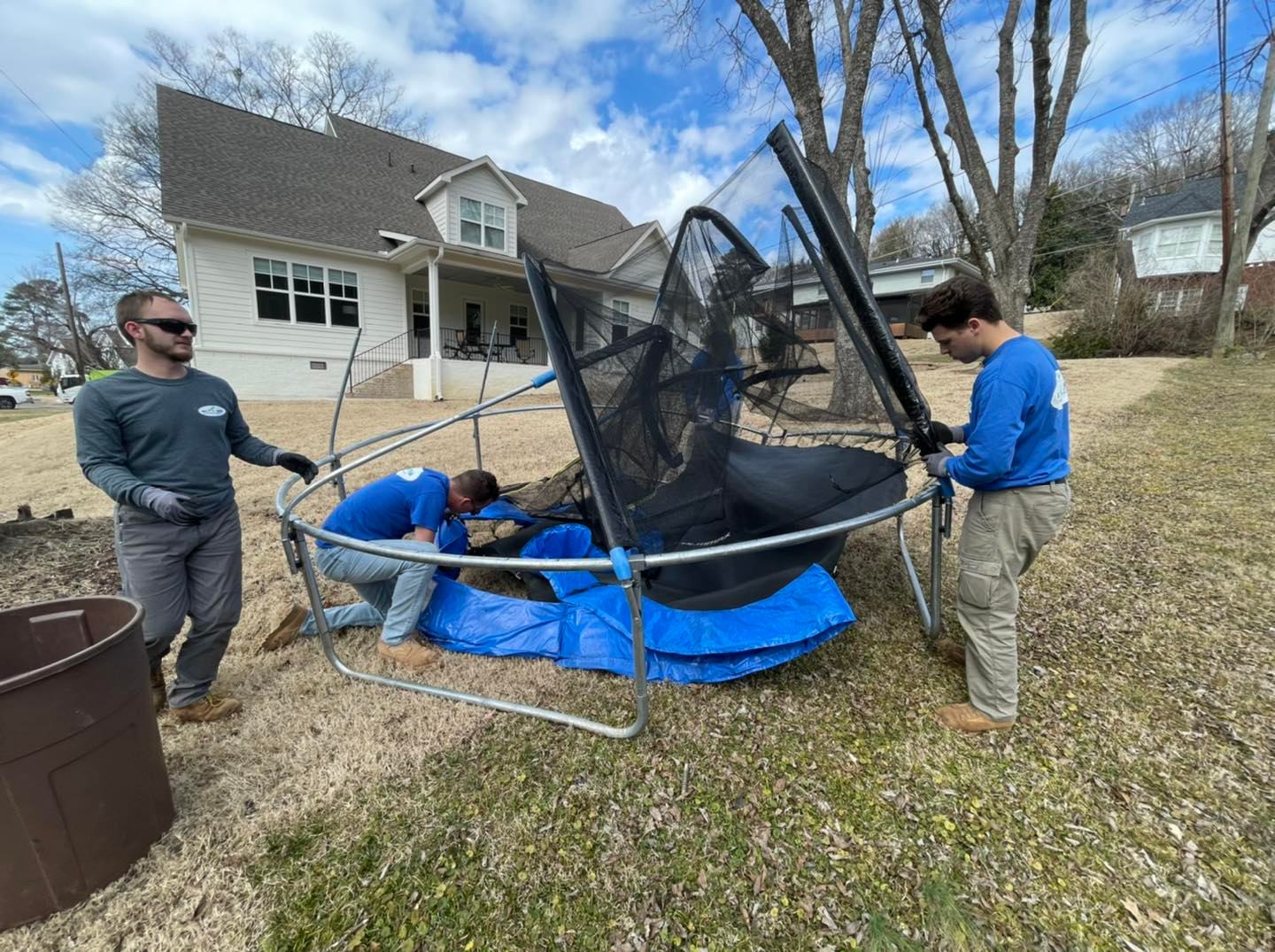 A group of men are working on a trampoline in front of a house.