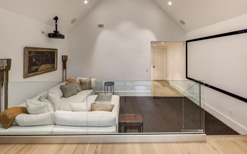 Home theater with a white sectional sofa, projector, and screen.