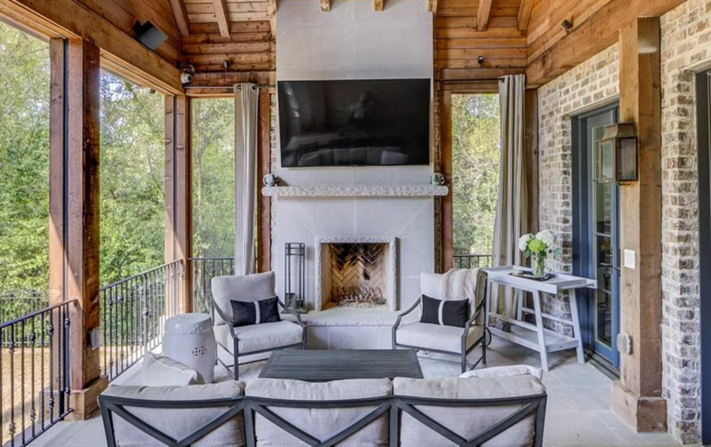 Outdoor living space with a fireplace, TV, seating, and brick accents.
