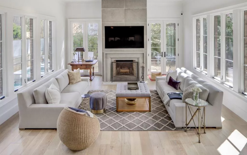 Bright living room with gray sofas, fireplace, large windows, and geometric rug.