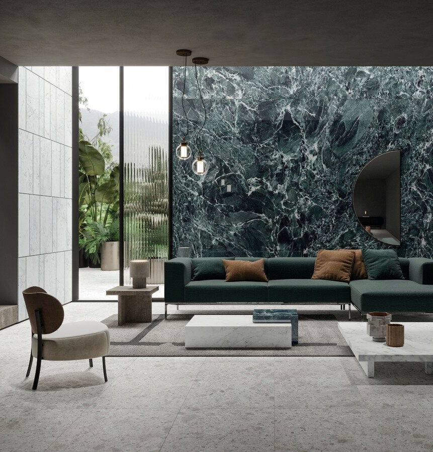 Modern living room with green sofa, marble wall, and large windows overlooking greenery.