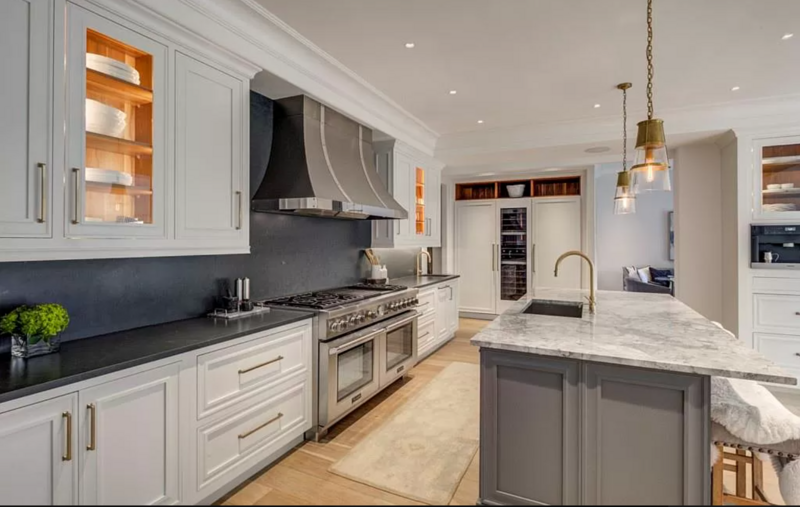 Bright kitchen with white cabinets, gray island, and stainless steel appliances.