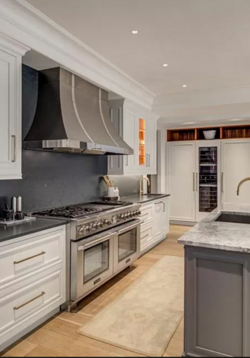 Elegant kitchen with white cabinets, stainless steel range, and dark backsplash.