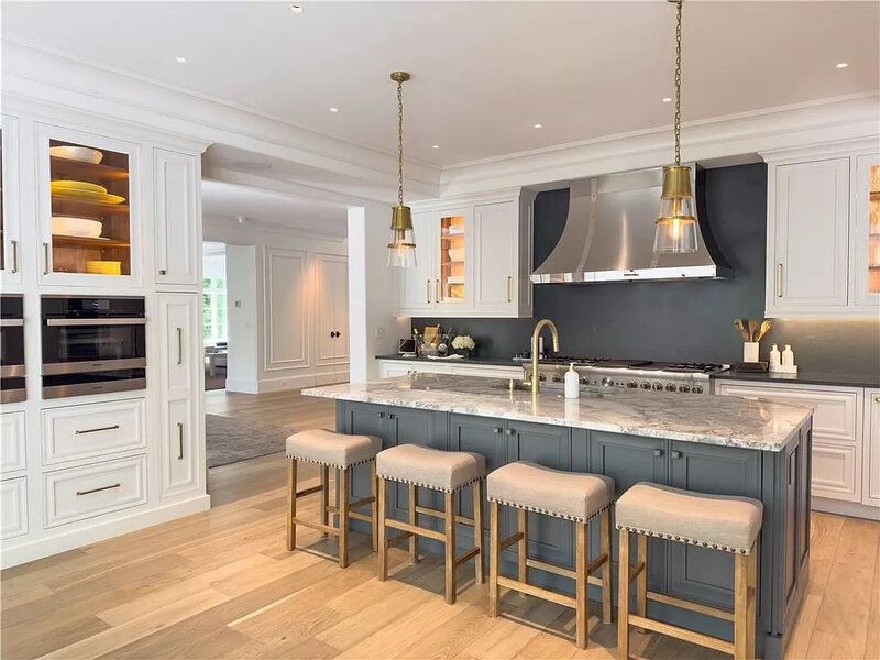 Elegant kitchen with light wood floors, white cabinets, and a gray island with seating.