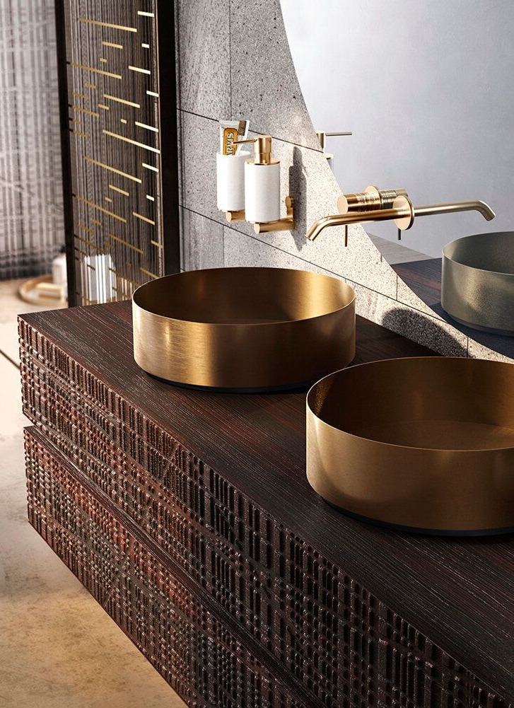 Two gold washbowls on a dark wood vanity, with matching fixtures and mirror in a luxury bathroom.