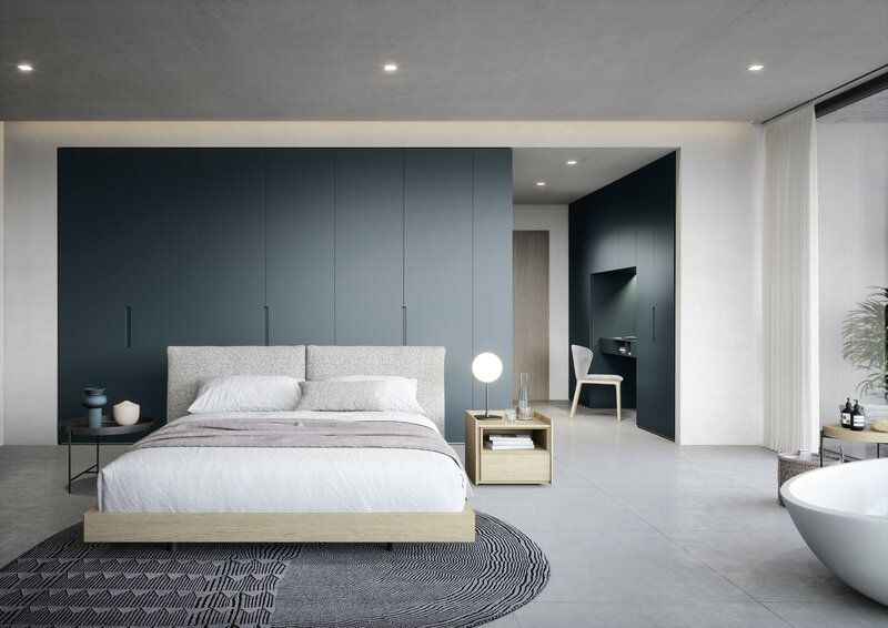 Modern bedroom with blue accent wall, bed, desk, and freestanding tub.