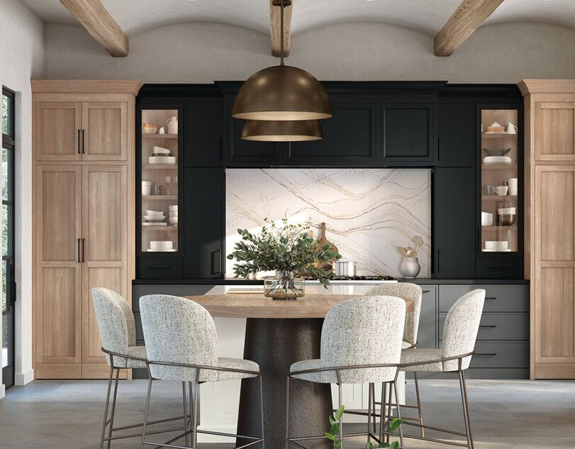Kitchen with black and light wood cabinetry, island with seating, and a large hanging light fixture.