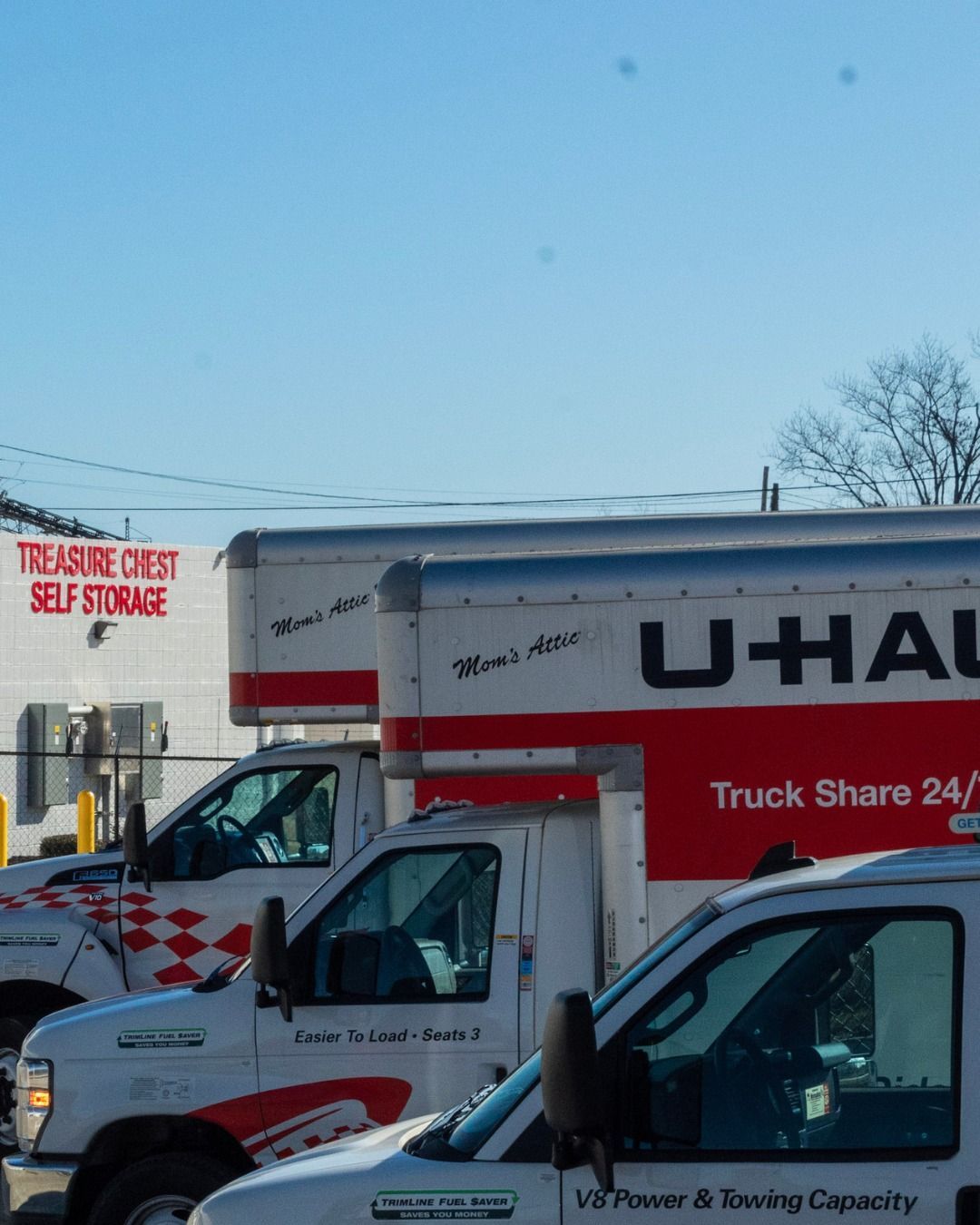 U-Haul trucks parked near a Treasure Chest Self Storage building under a blue sky.