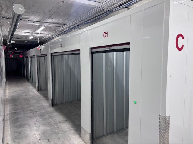 A hallway in a self-storage facility featuring a row of open white units labeled